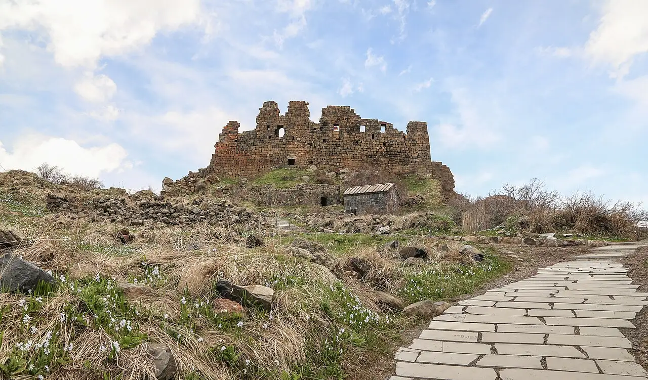 The walls of Amberd fortress and the Vahramashen church on a green spur of Mount Aragats