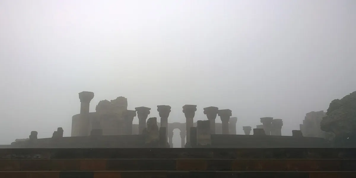 Re-erected columns and circular foundations of ruined Zvartnots Cathedral in morning mist