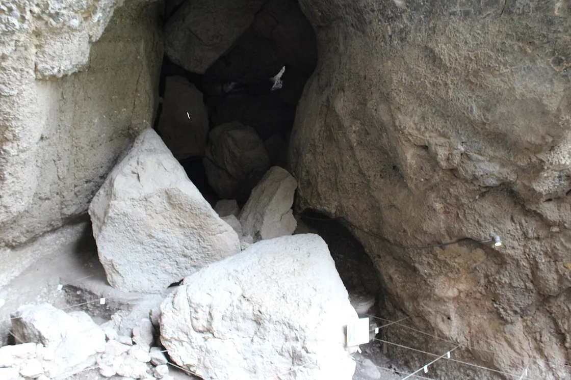 A dim inner chamber of Areni-1 cave with fallen boulders and excavation survey strings across the floor
