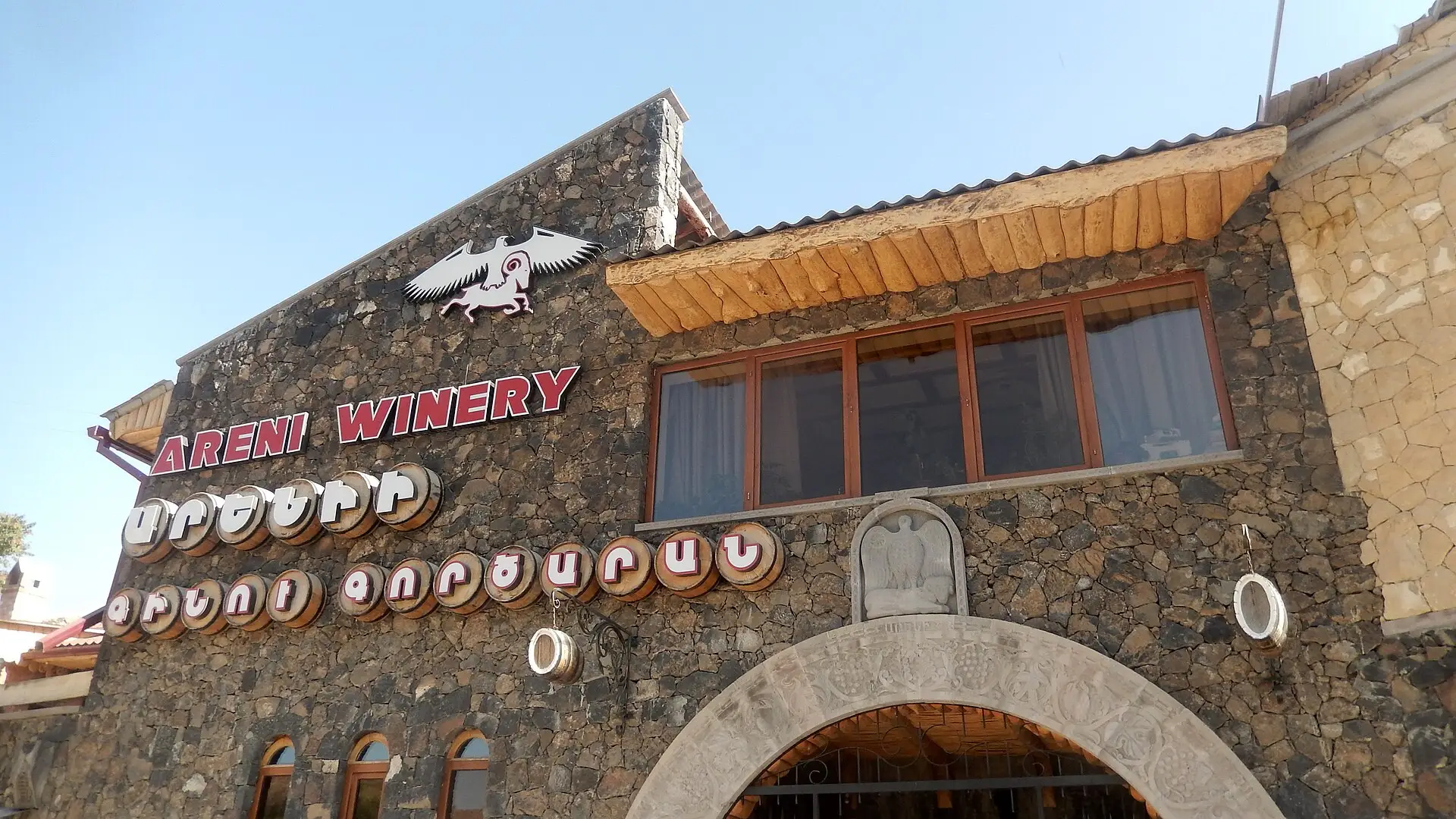 Rows of vines and the Areni winery buildings under a clear sky in Vayots Dzor wine country