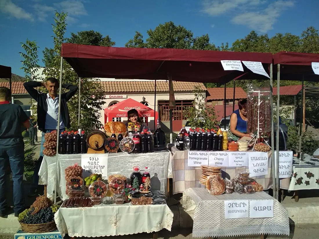 Visitors holding wine glasses among the festival stalls in Areni village