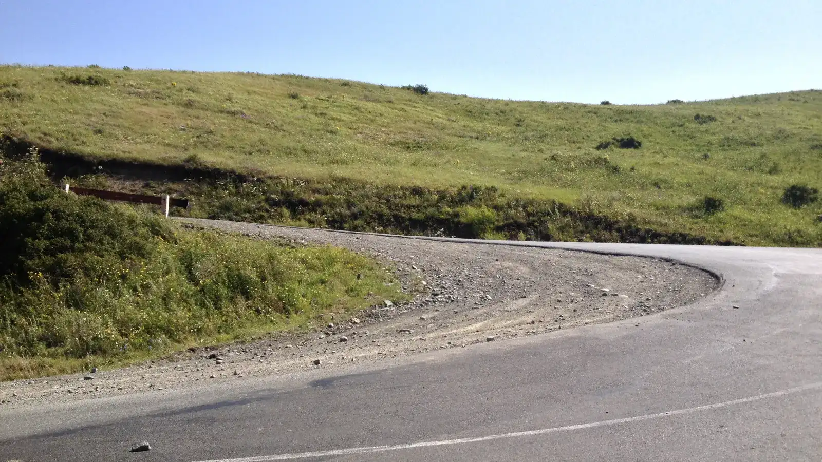An empty paved road curving over bare green highland near the Vorotan pass in southern Armenia