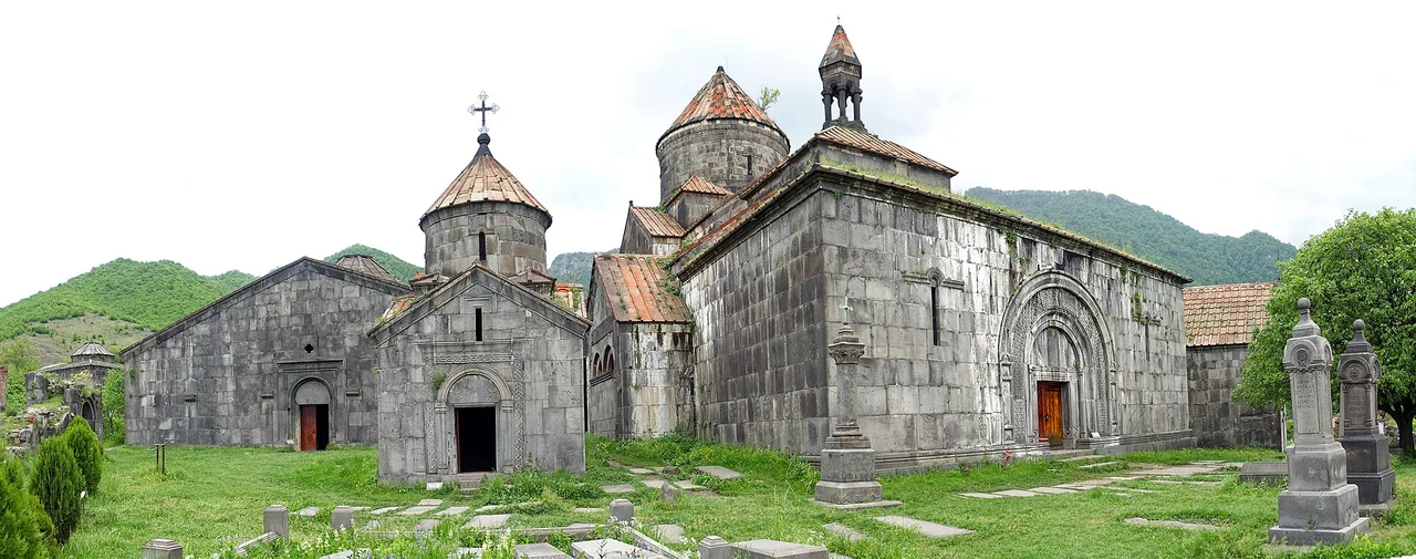 The clustered domes and grey stone churches of Haghpat monastery on green grass