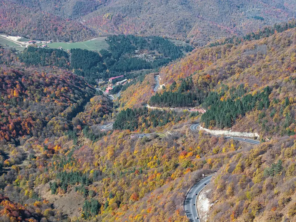 Hairpin bends of the M4 highway cutting through autumn forest on the approach to Dilijan
