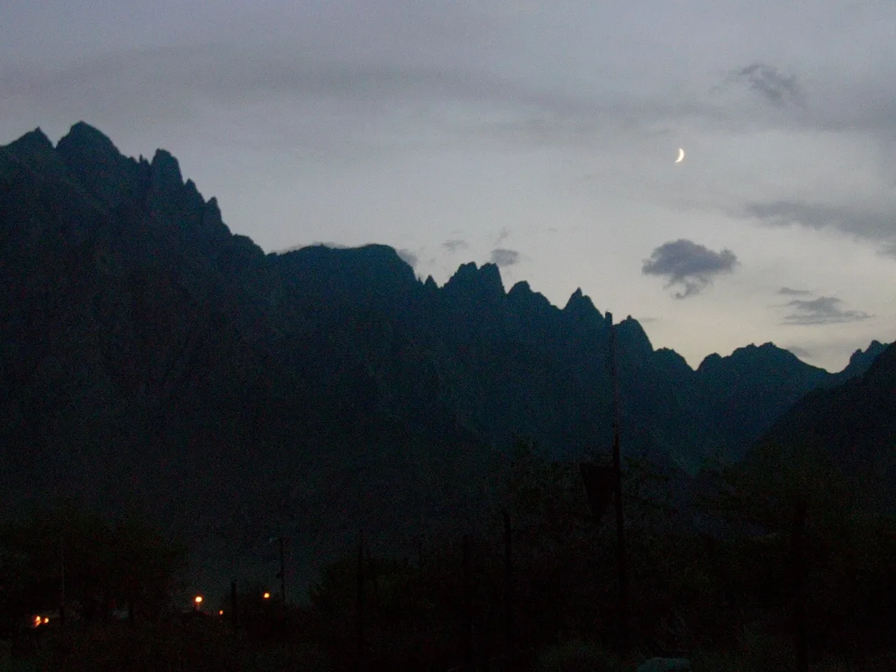 Silhouetted mountains along the Armenia-Iran border at dusk with a crescent moon overhead