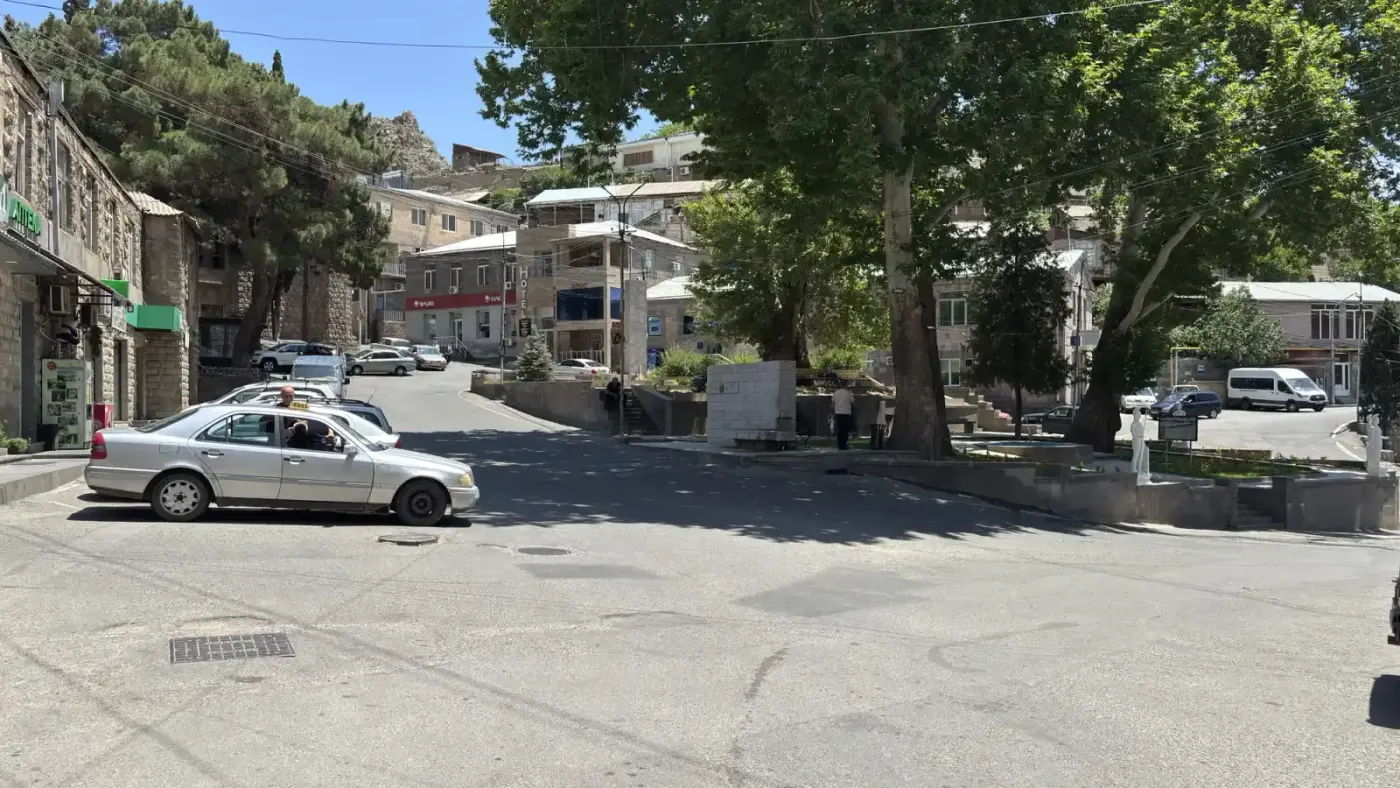 A taxi crossing the central square of Meghri, the last Armenian town before the border with Iran, with old town ruins on the hill behind