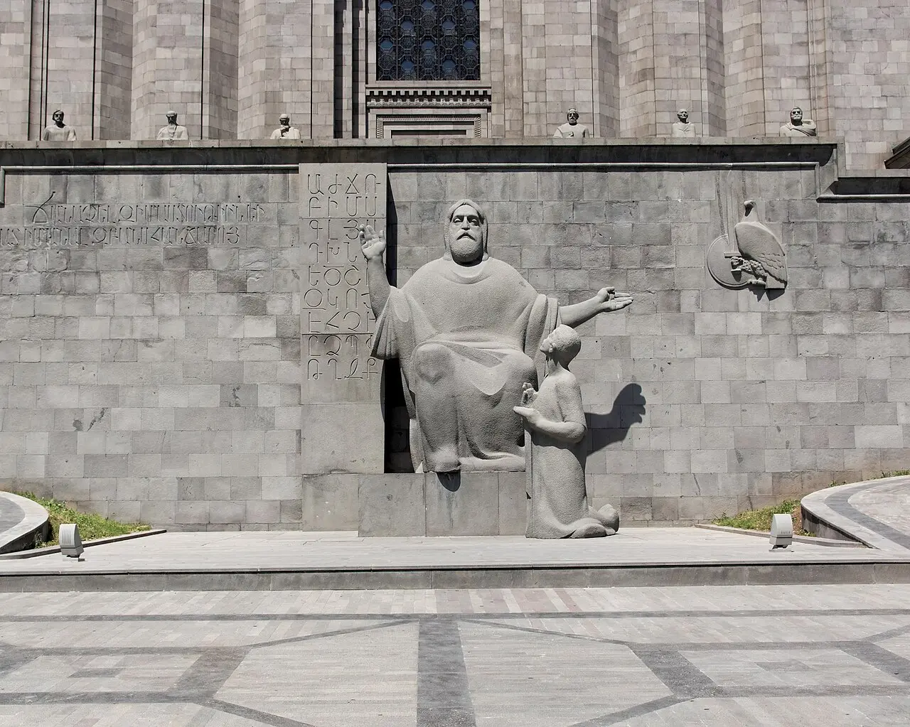 The stone statue of Mesrop Mashtots beside a carved tablet of the Armenian alphabet at the Matenadaran in Yerevan