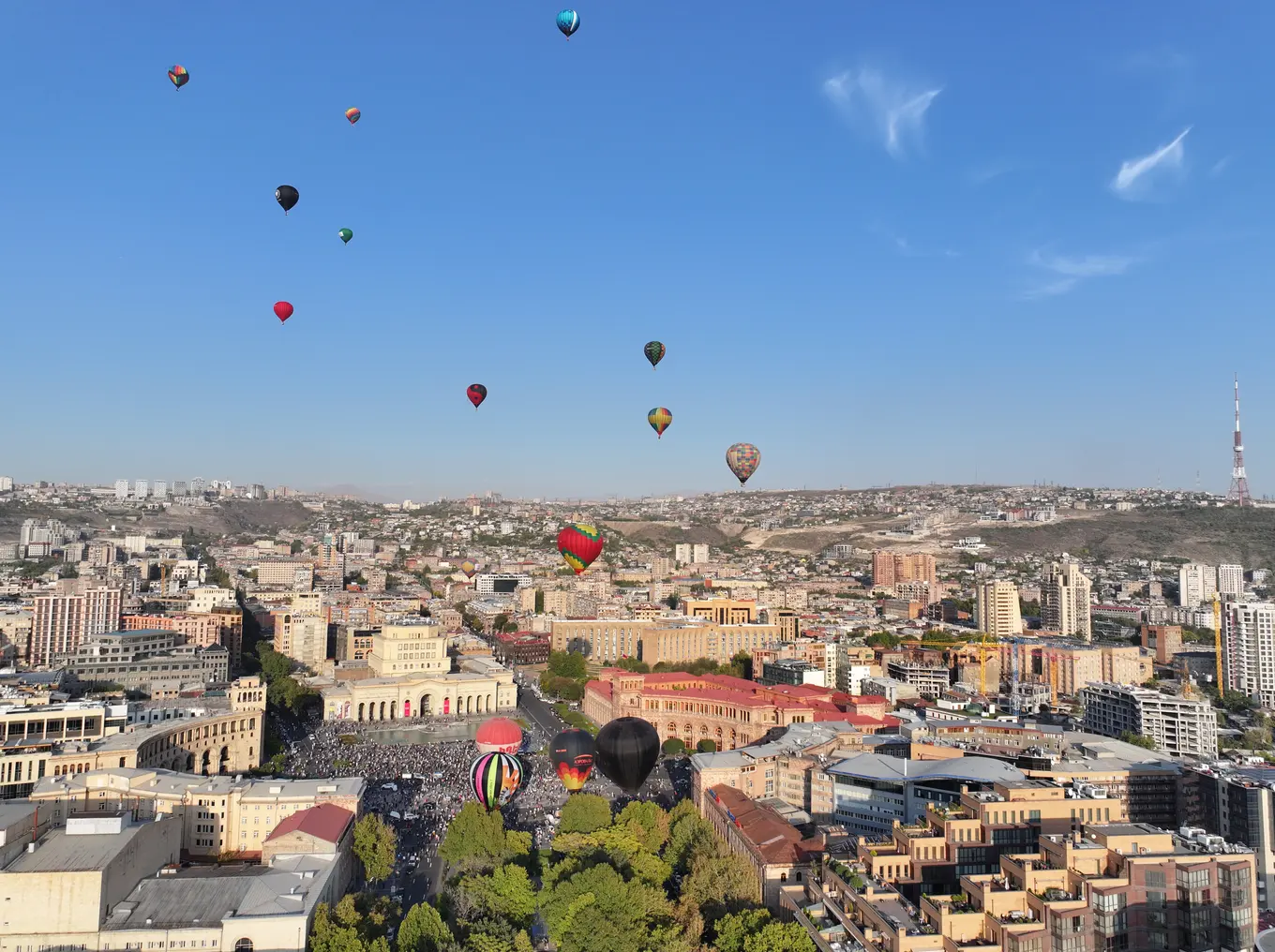 Hot-air balloons floating over the pink-tuff buildings of Republic Square in Yerevan on a bright day