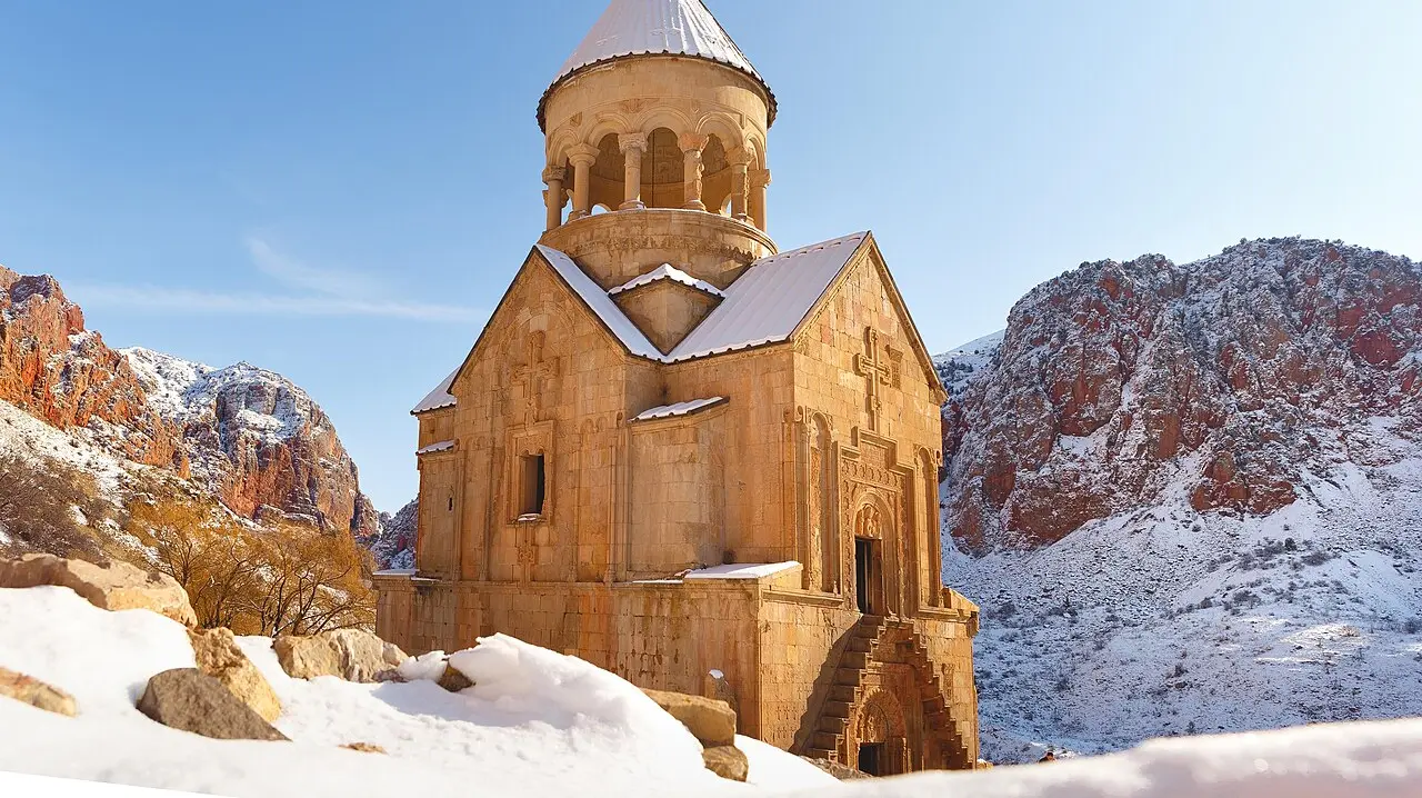 Noravank monastery under a dusting of snow against its red cliffs on a bright winter day in southern Armenia