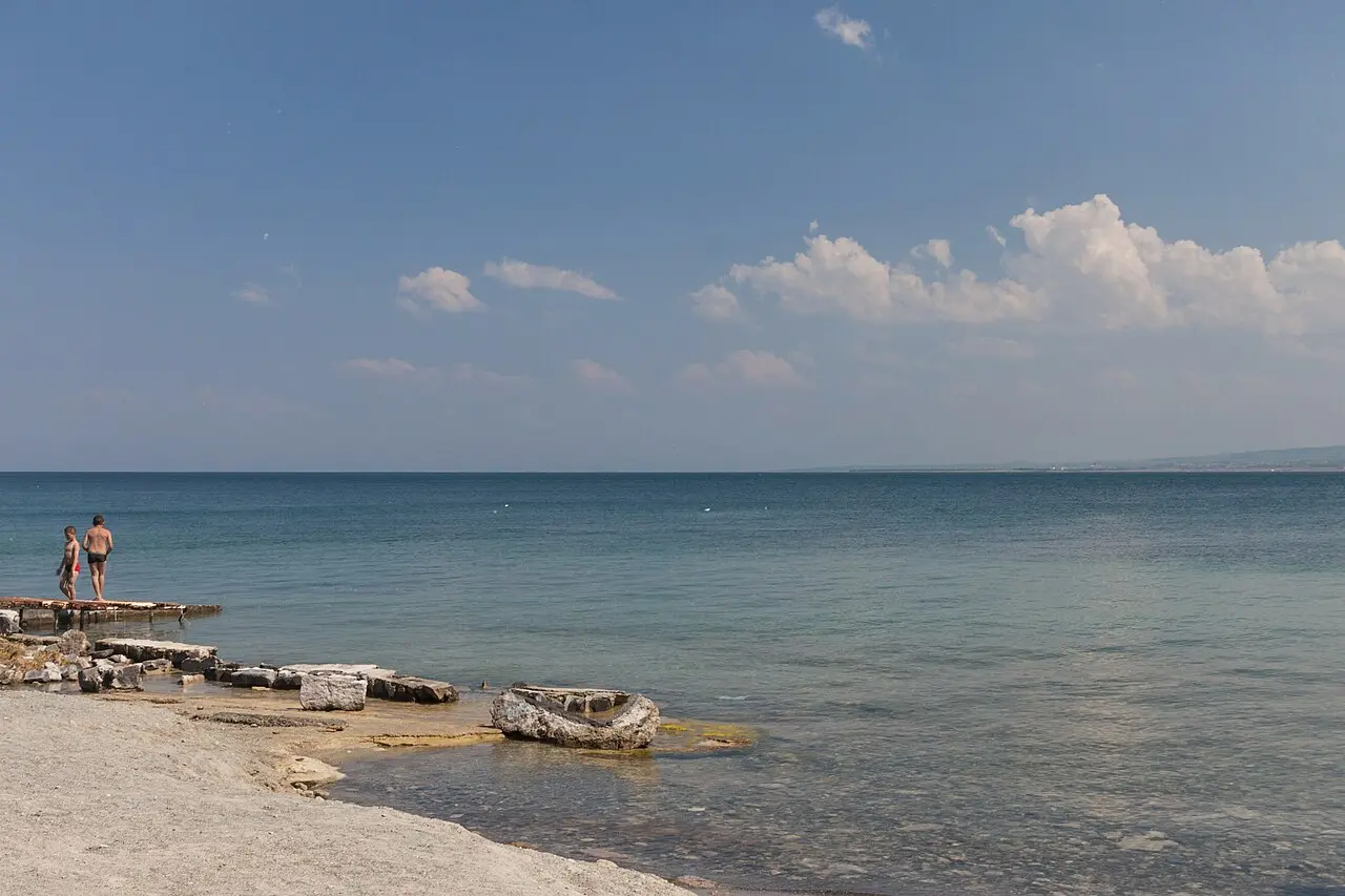 The blue water of Lake Sevan under a bright summer sky with a couple by the shore