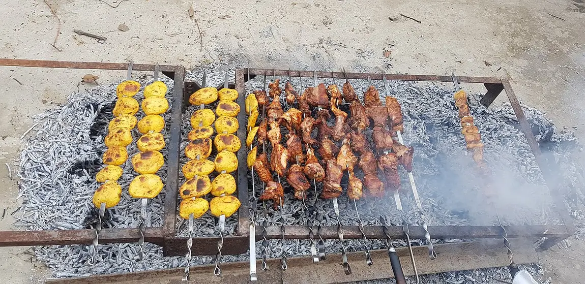 Skewers of Armenian khorovats barbecue cooking over open coals