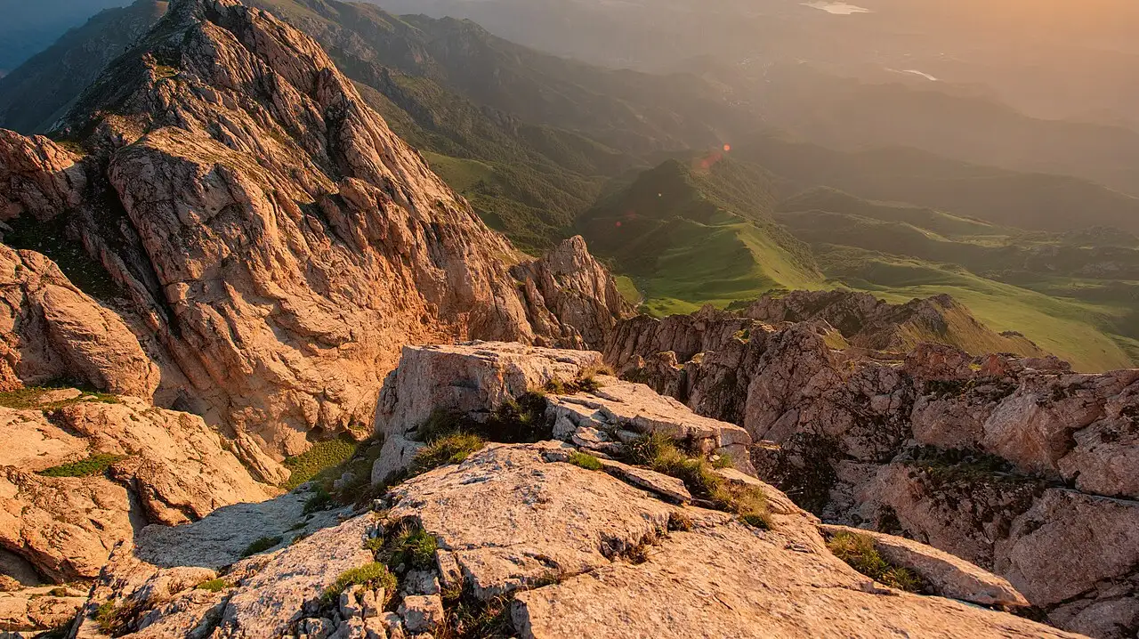 The rocky summit ridge of Mount Khustup catching golden sunrise light above green valleys near Kapan in southern Armenia