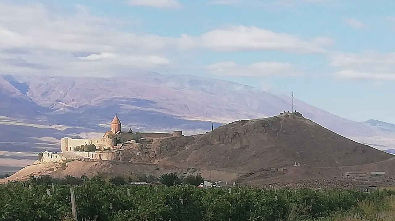 Khor Virap monastery on its hill above the vineyards of the Ararat plain, with the foothills of Mount Ararat rising behind