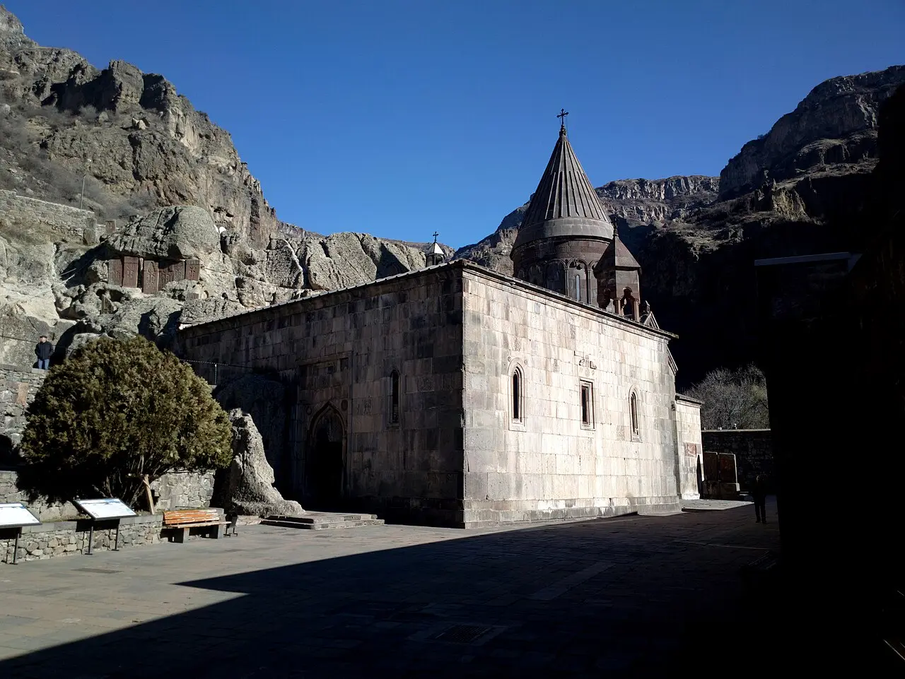 The stone church of Geghard monastery standing directly against the grey cliffs of the Azat gorge