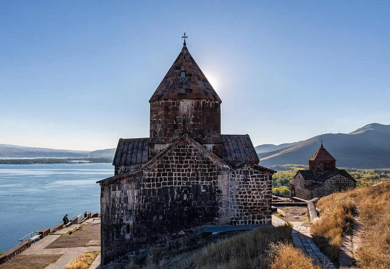 The dark tuff church of Sevanavank on its headland above the blue water of Lake Sevan