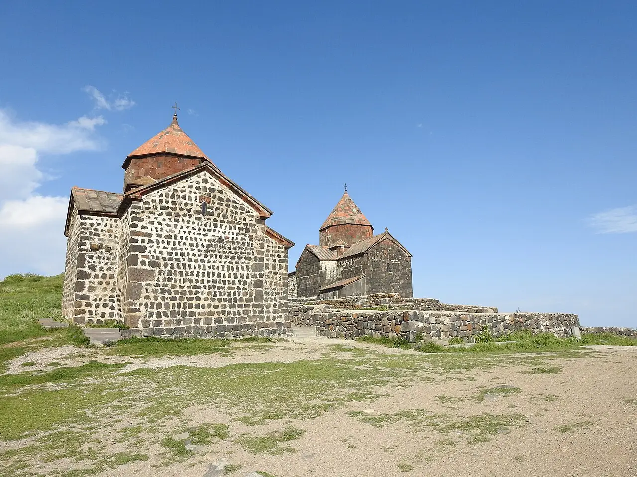 The two black-tuff churches of Sevanavank monastery on the Lake Sevan peninsula under a blue sky