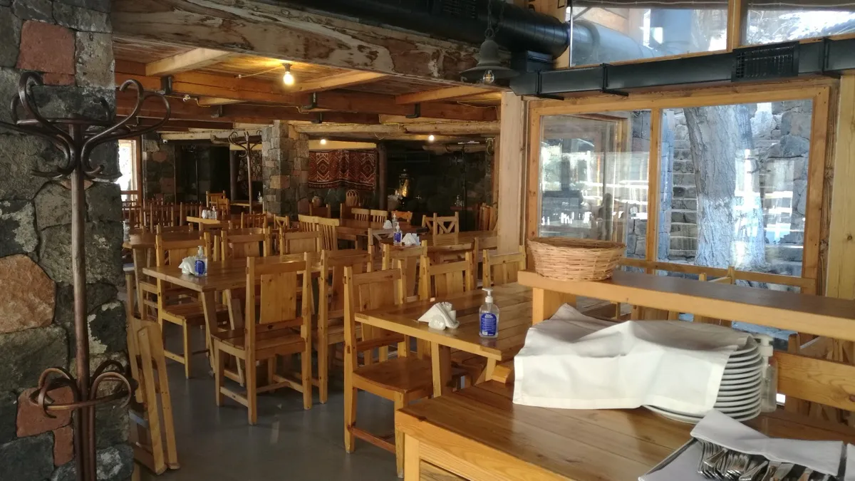 The wooden-beamed dining room at Cherkezi Dzor with stone pillars and tables set for service