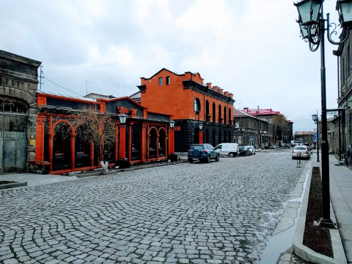 The red-painted arcaded facade of Poloz Mukuch Beerhouse on a cobblestone street in old Gyumri
