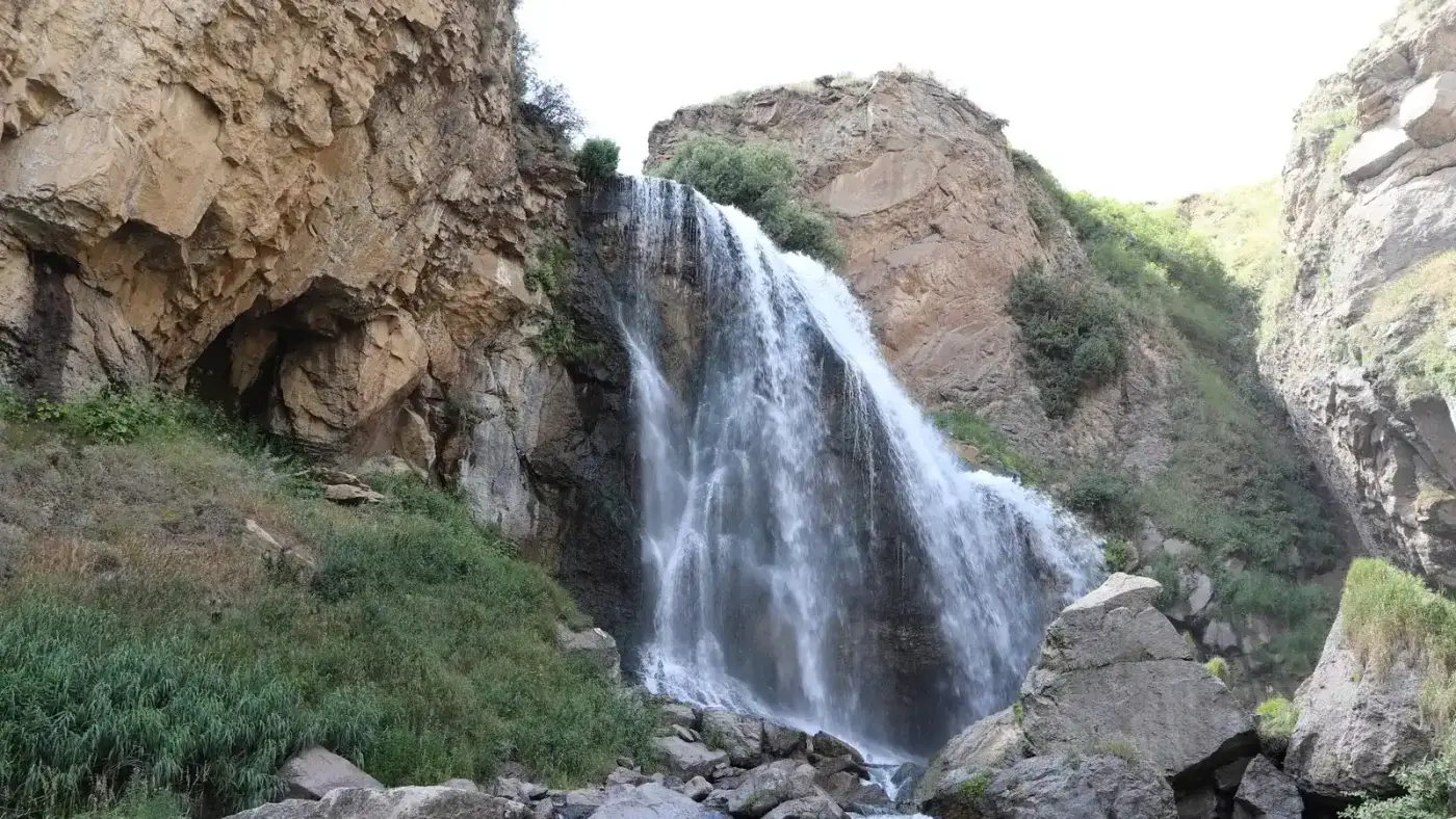 The Trchkan waterfall dropping clear off a tawny rock lip into a boulder-filled gorge on the Shirak and Lori border