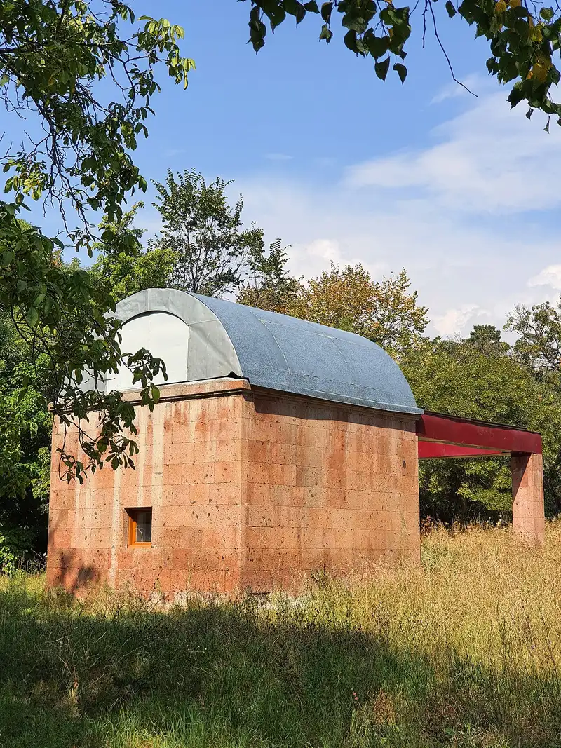A white observatory dome among pine trees on the slope above Byurakan village