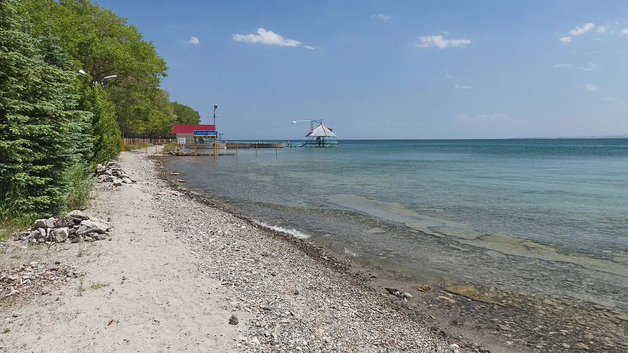 The wide blue expanse of Lake Sevan and its mountain shore seen from the Sevan peninsula under a summer sky