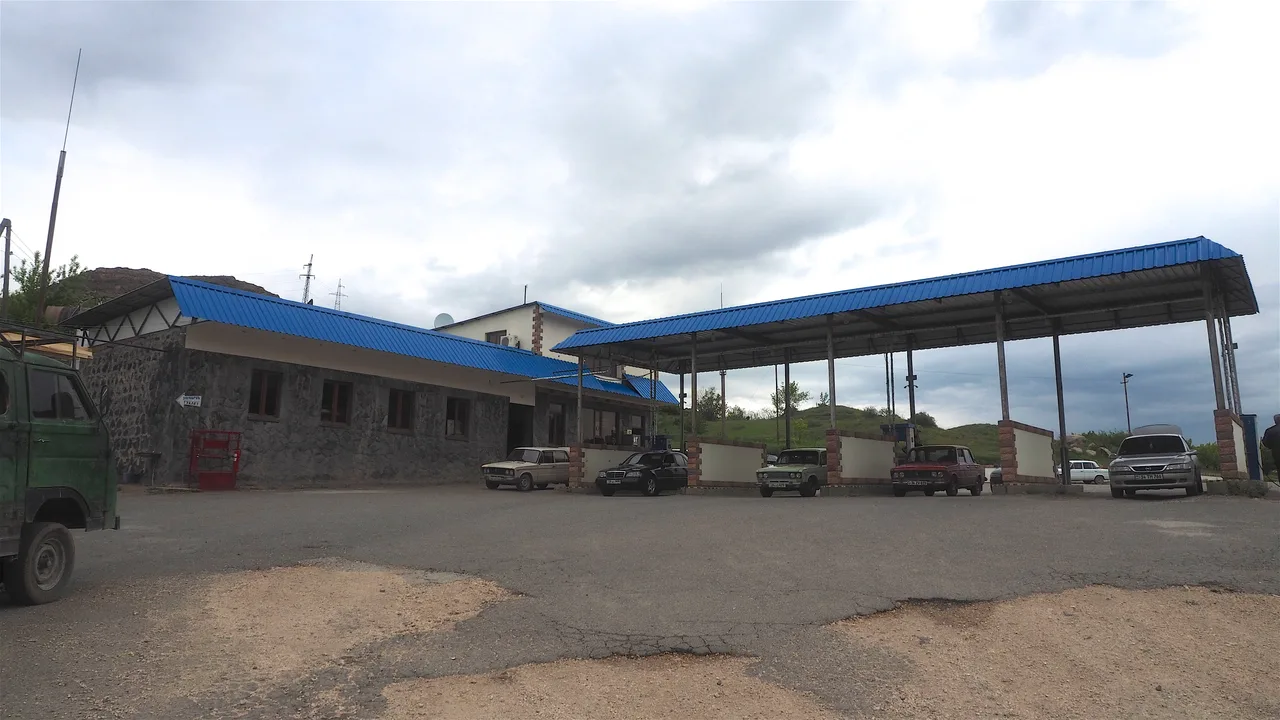 Older Lada cars parked around the pumps at a small roadside filling station in Armenia