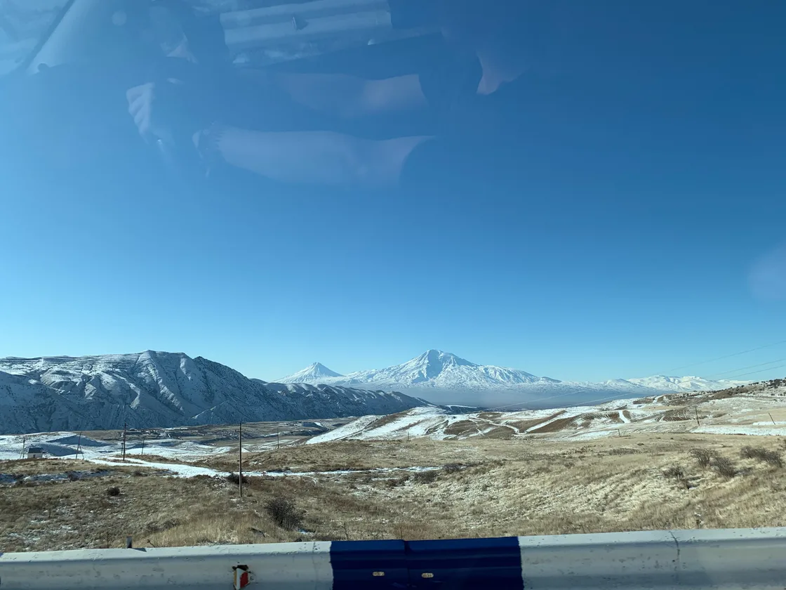 A snow-lined road through a bleak Armenian landscape in January with grey winter skies overhead