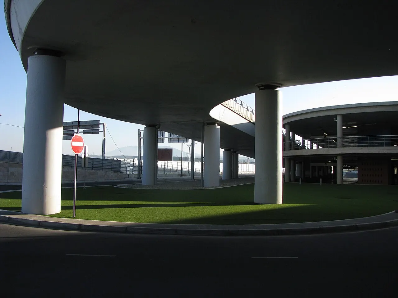 The roadway running under the Zvartnots terminal canopy, where arrivals spill out toward taxis, buses and the rental parking
