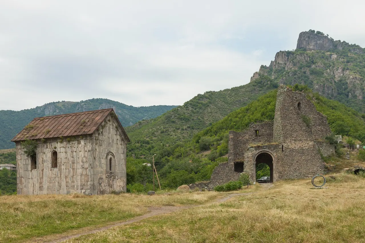 The church and ruined fortress gate of Akhtala on their grassy spur with a rock crag rising behind