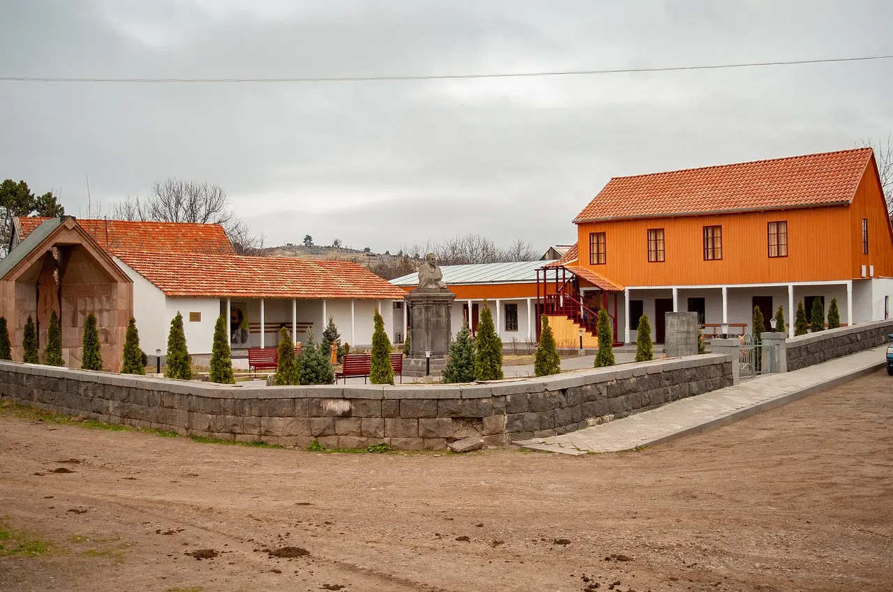 The walled compound of the Tumanyan house-museum in Dsegh, an orange timber house above a white colonnaded gallery