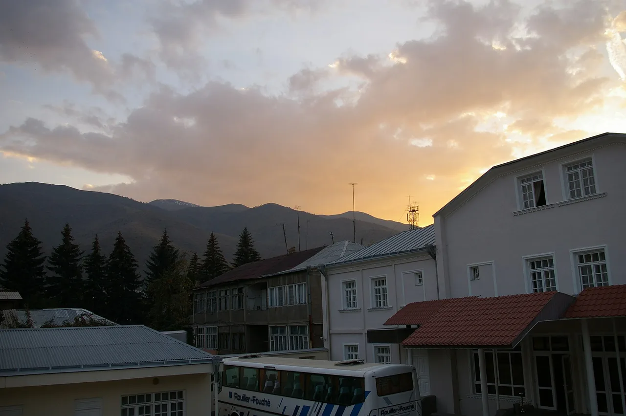 Low roofs and Soviet-era houses of Vanadzor at sunset with the wooded Pambak ridge behind