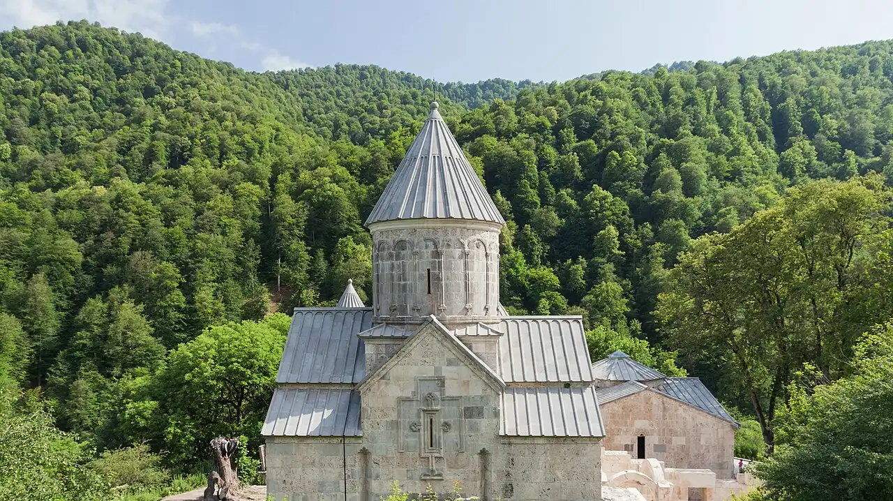 The stone churches of Haghartsin monastery standing in a clearing of dense green forest on the wooded slopes above Dilijan
