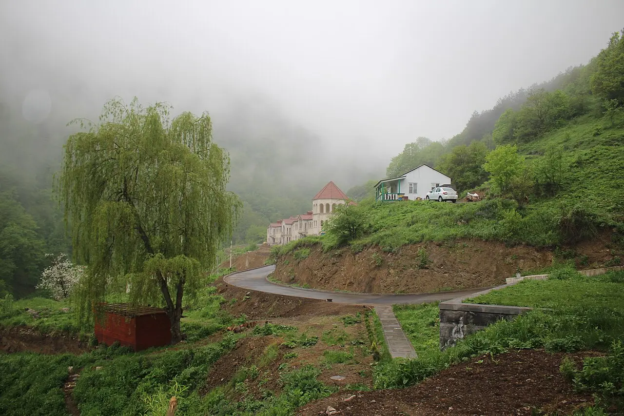 The town of Dilijan spread along a green valley floor, its houses backed by steep forested mountains under a bright sky