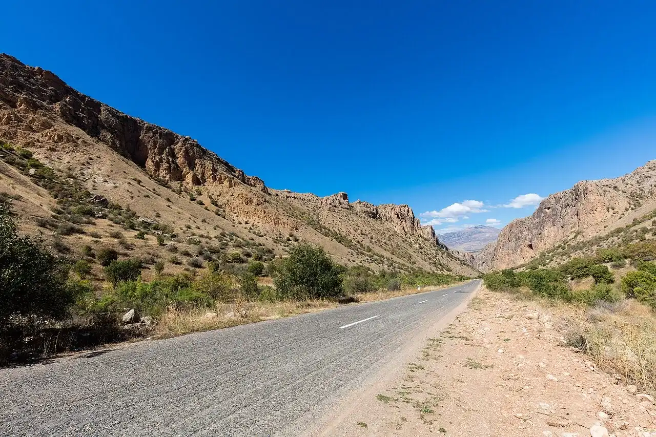 An empty paved road winding through a rocky canyon on the way to Noravank monastery in southern Armenia