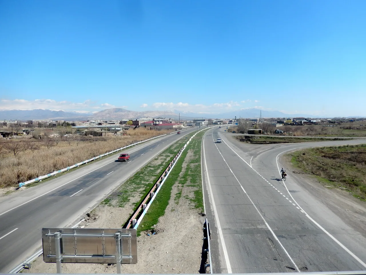 A wide open two-lane M2 highway running across dry hills under a big sky in southern Armenia