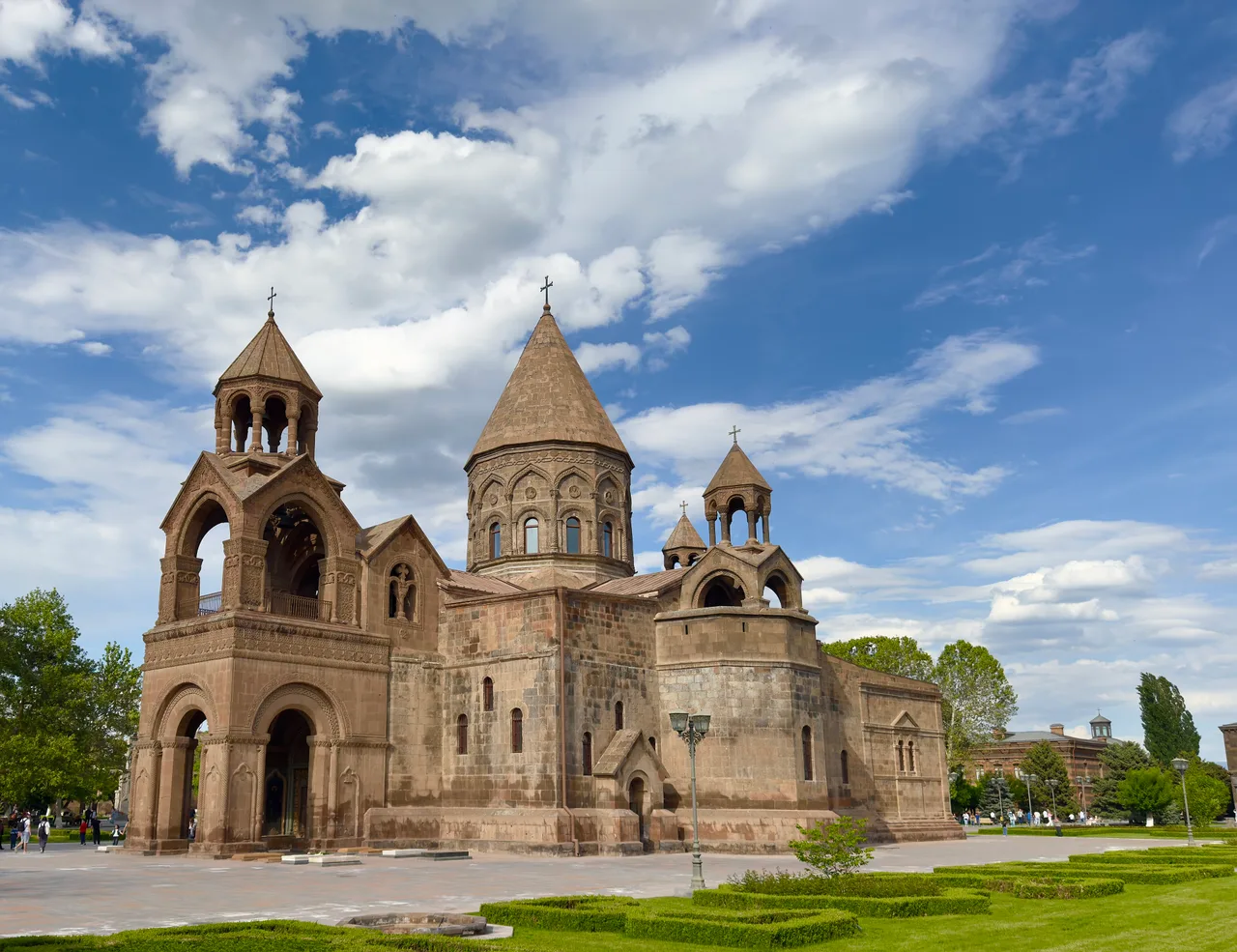 The stone facade and cross-topped dome of Etchmiadzin Cathedral after its restoration, seen across the cathedral courtyard