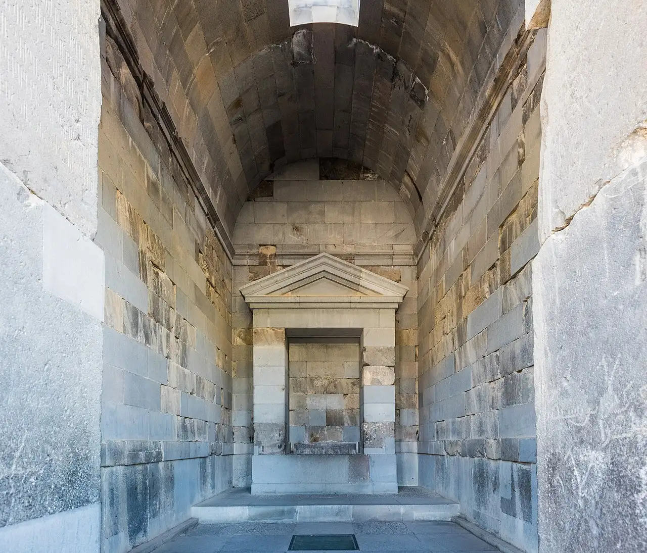 The vaulted stone interior of the Garni temple cella, with a small carved pediment shrine on the far wall