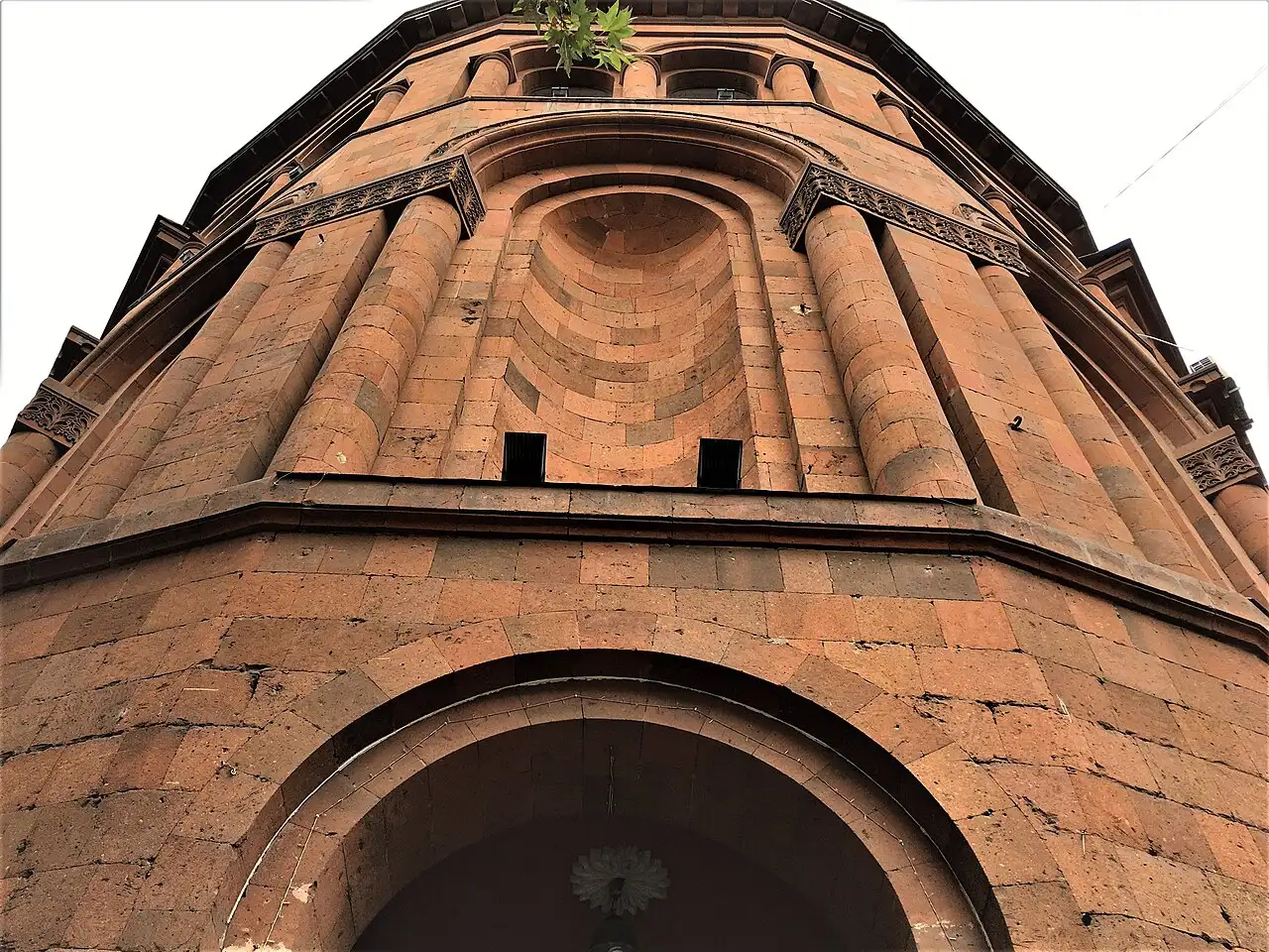 The reddish tufa stone entrance of the Nairi Cinema on Mashtots Avenue in Yerevan seen from below