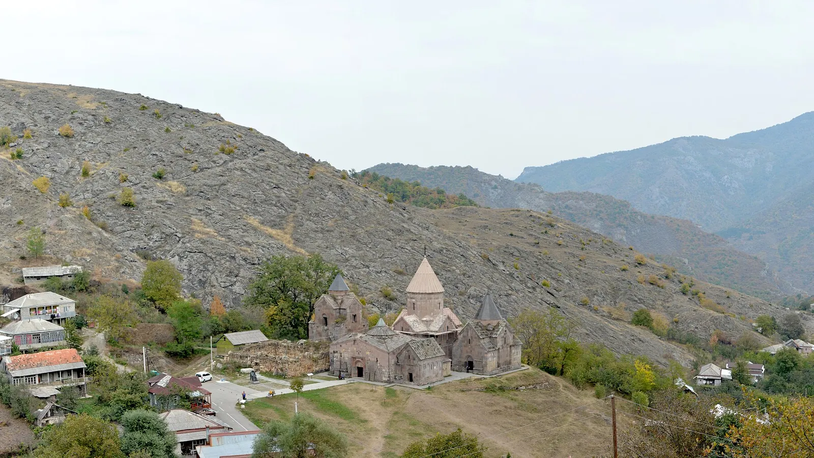 Elevated autumn view of Goshavank monastery and Gosh village at the foot of a bare mountainside in Tavush province
