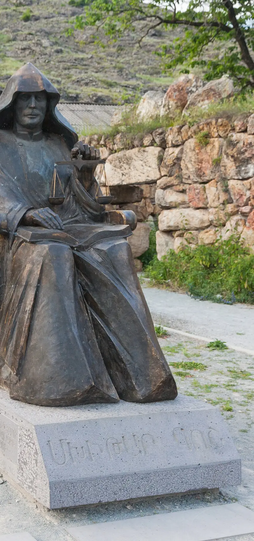 Bronze statue of Mkhitar Gosh seated with an open law book on his lap and a set of scales in one hand