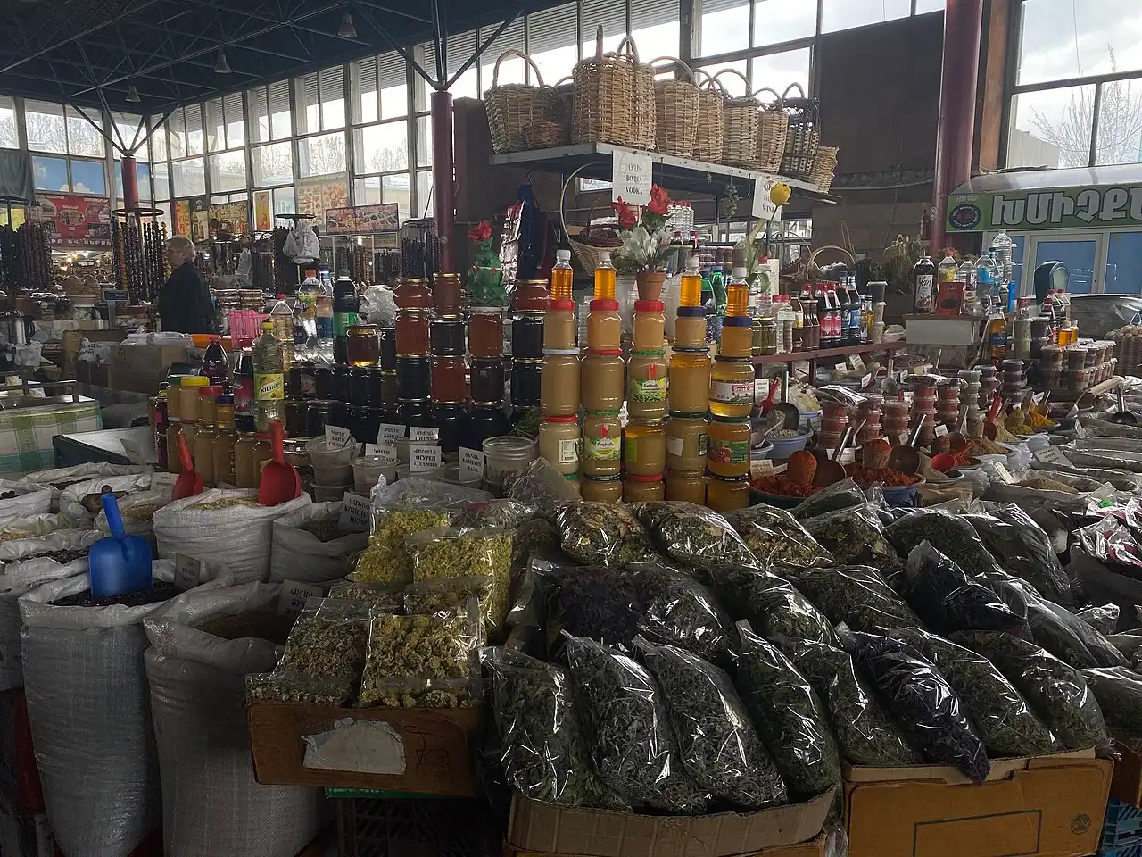 Glass jars of honey and bunches of dried herbs on a market stall at GUM Market in Yerevan
