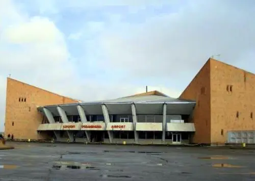 A wide exterior view of the Gyumri Shirak Airport terminal building under a cloudy sky