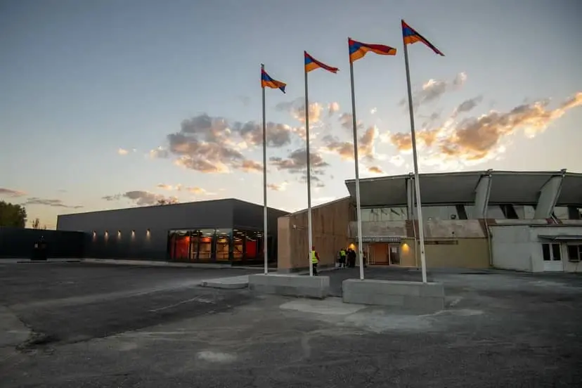 The new arrivals terminal at Gyumri Shirak Airport at dusk, with a row of Armenian flags out front