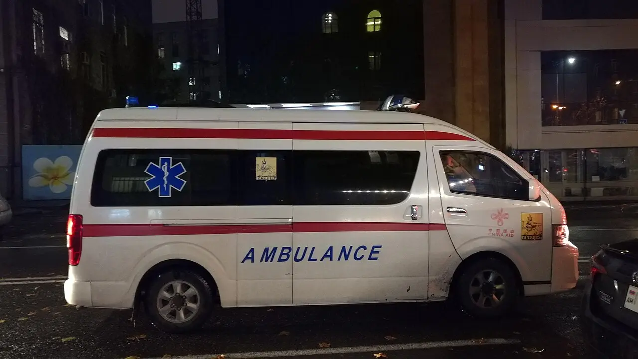 A white and red Armenian ambulance van parked on a street in Yerevan at night