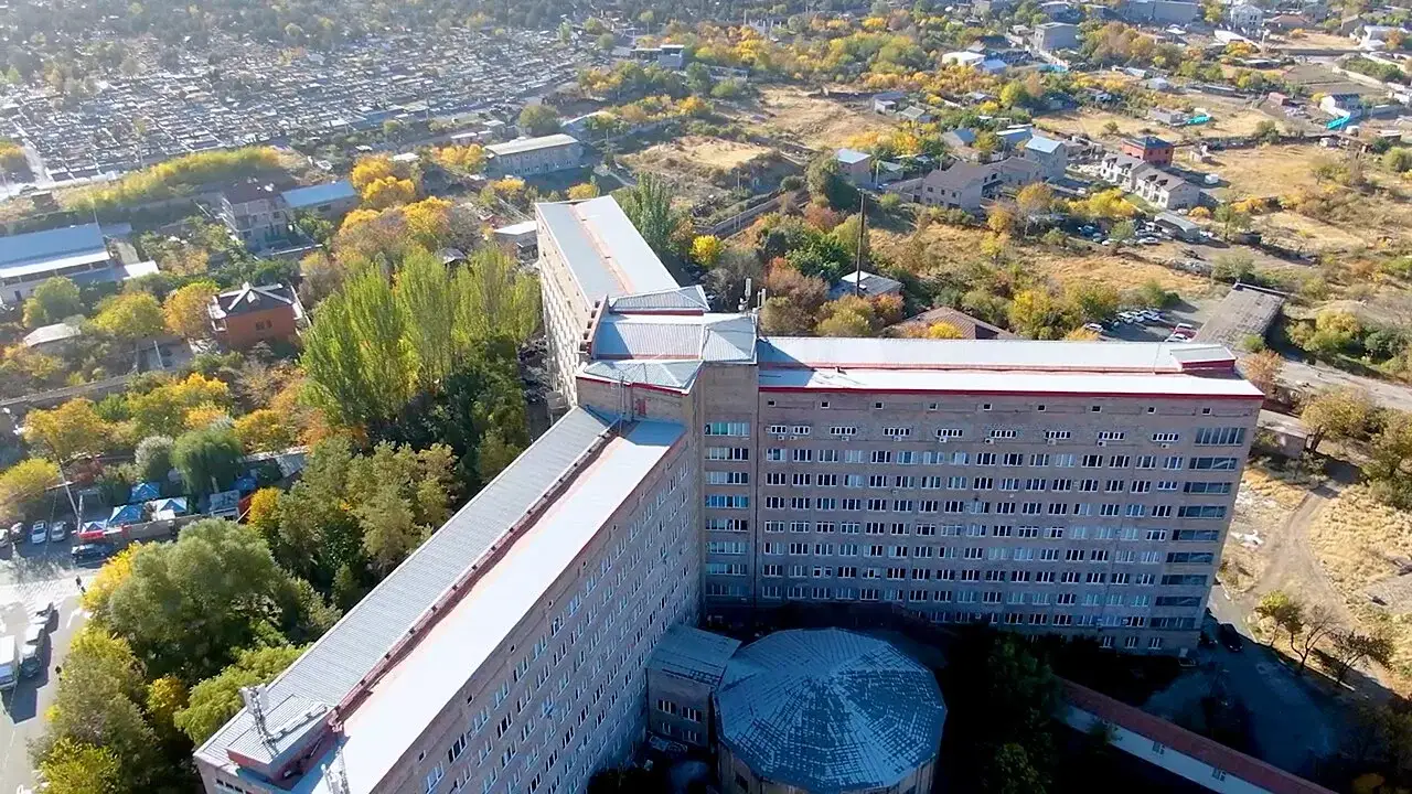 Aerial view of a large multi-storey hospital building in Yerevan surrounded by autumn trees