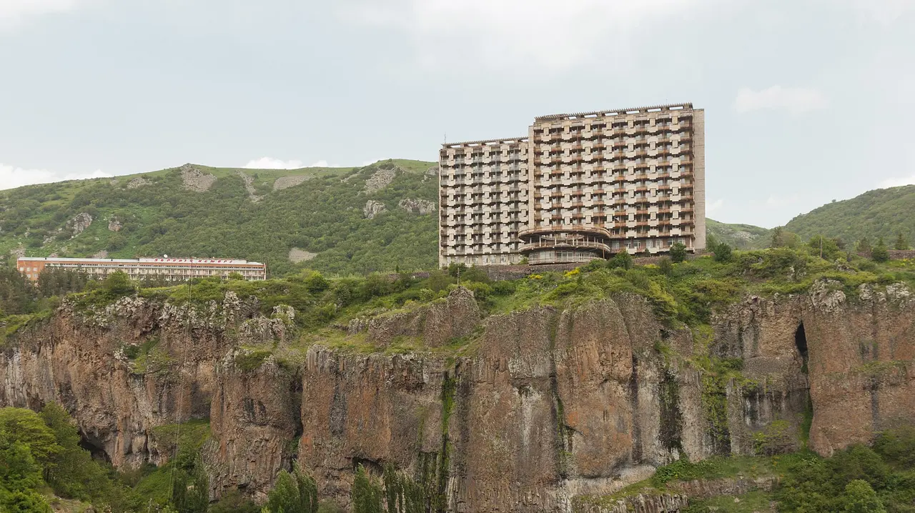 A large spa hotel perched on the edge of the basalt Arpa gorge above Jermuk, green hills behind