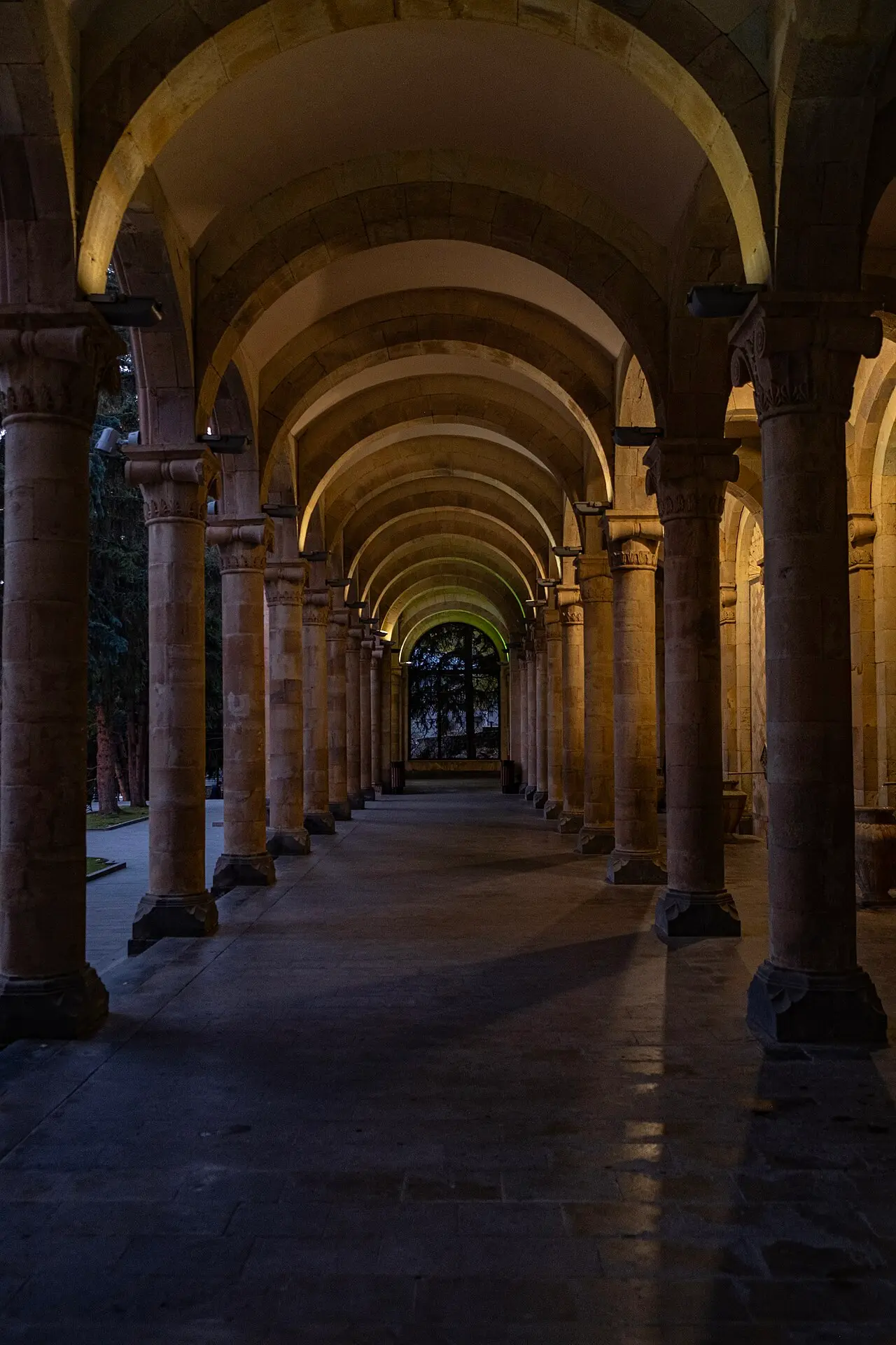 The arcaded stone building of the Jermuk Mineral Water Gallery among autumn trees, its long colonnade housing the drinking taps