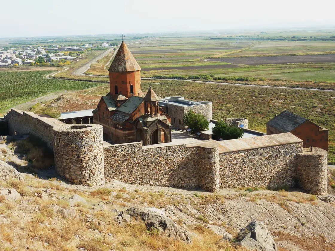 The fortified stone walls, round towers and red-tuff church of Khor Virap monastery on its hill above the Ararat plain