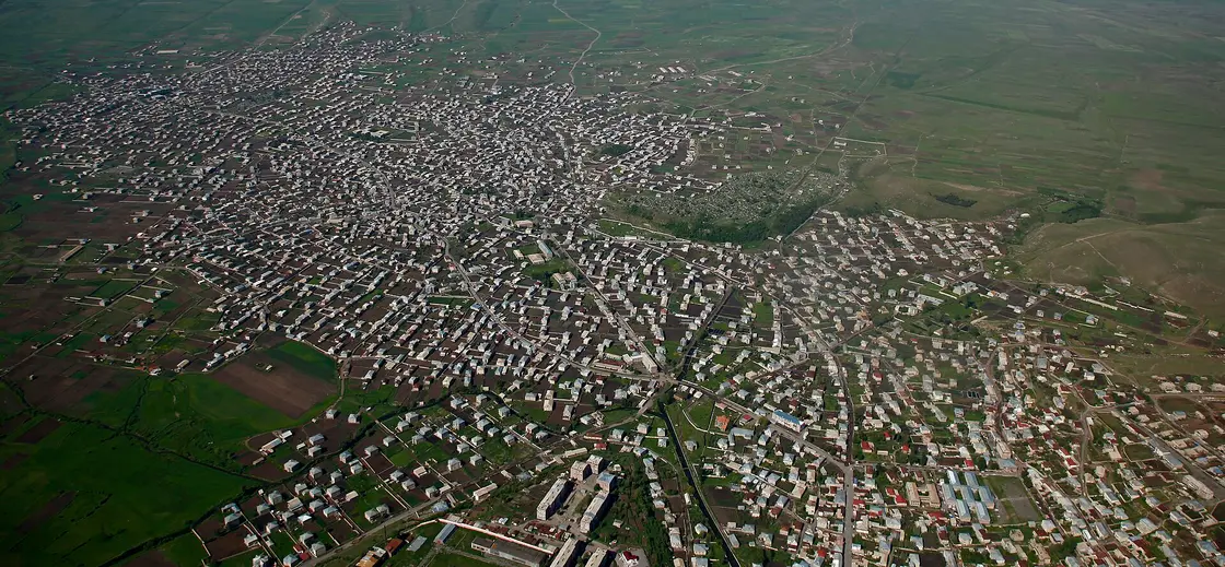 An aerial view over the low rooftops of Gavar town with the hills of Gegharkunik behind