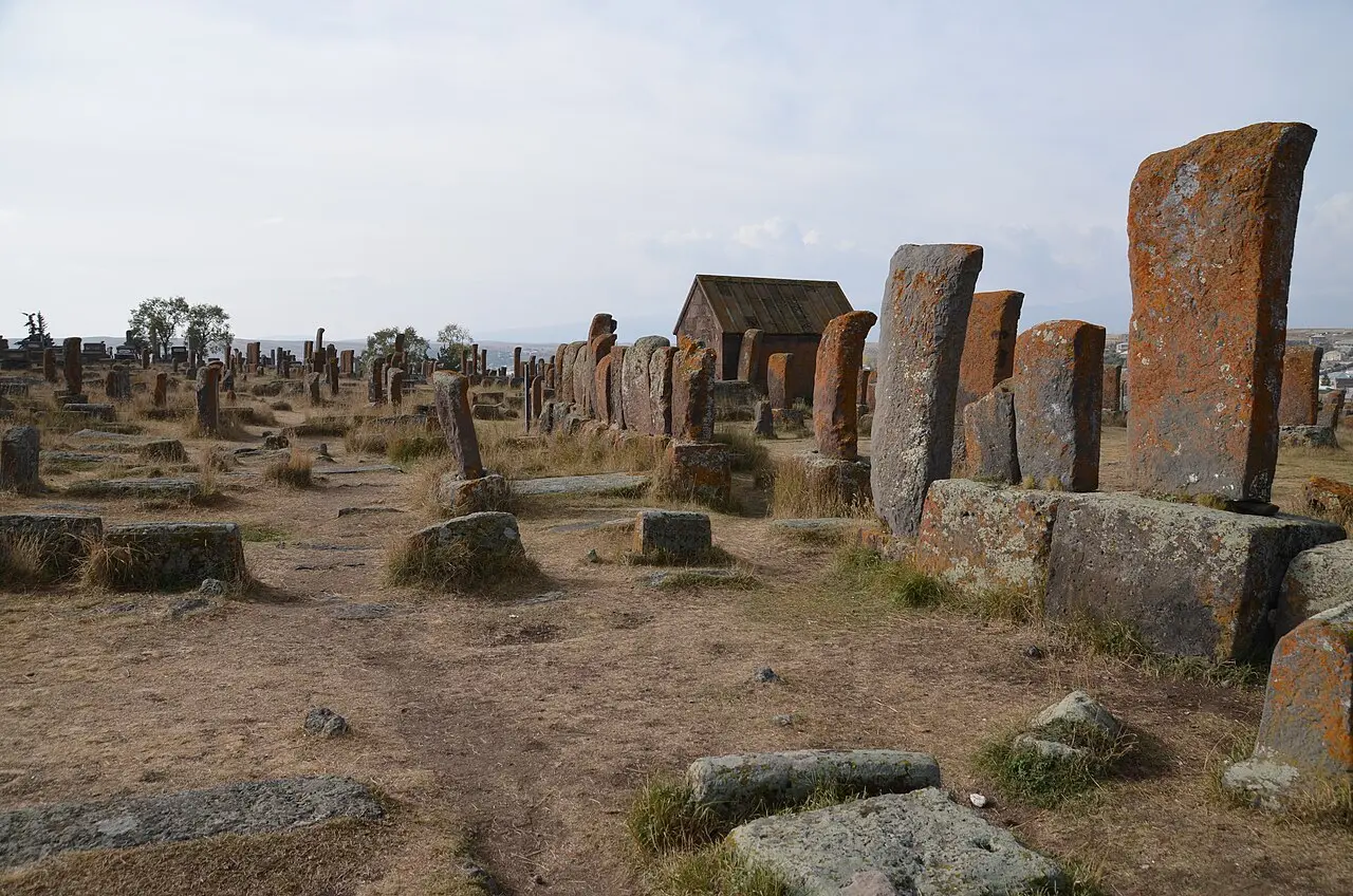 Rows of carved medieval khachkars standing in the grass at Noratus cemetery near Lake Sevan